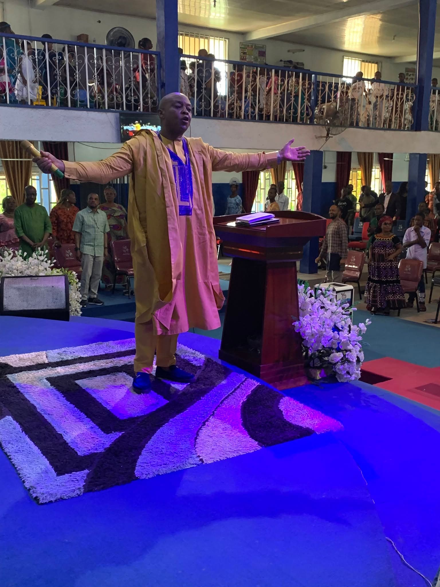 A minister standing with arms raised on the platform