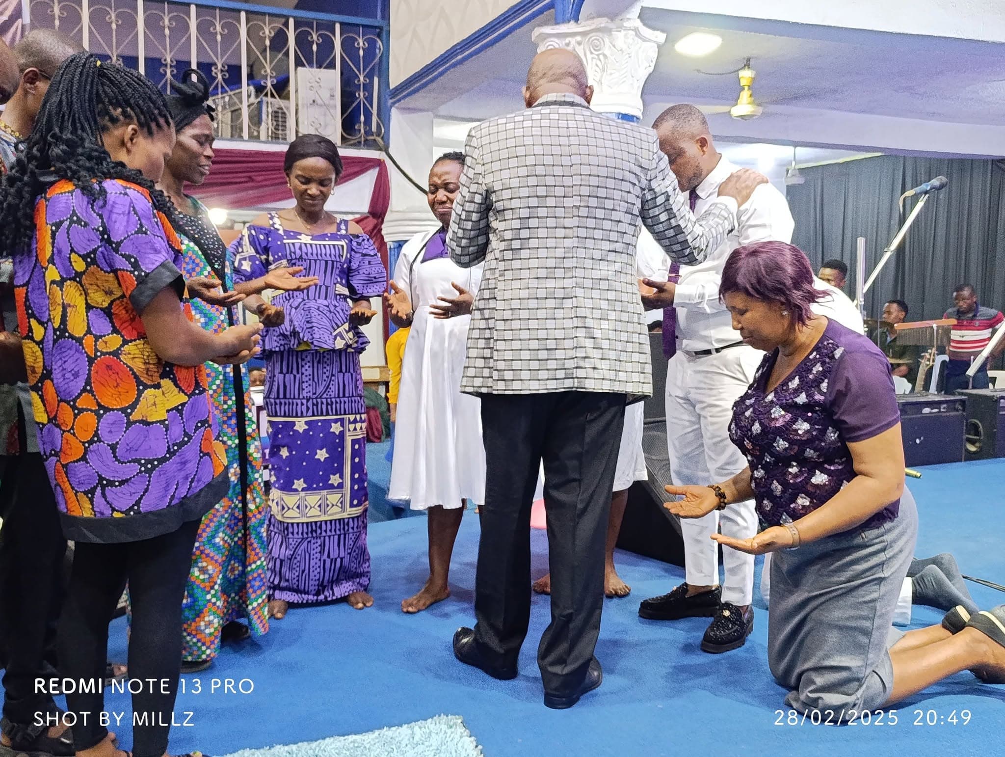 A minister praying with members at the altar
